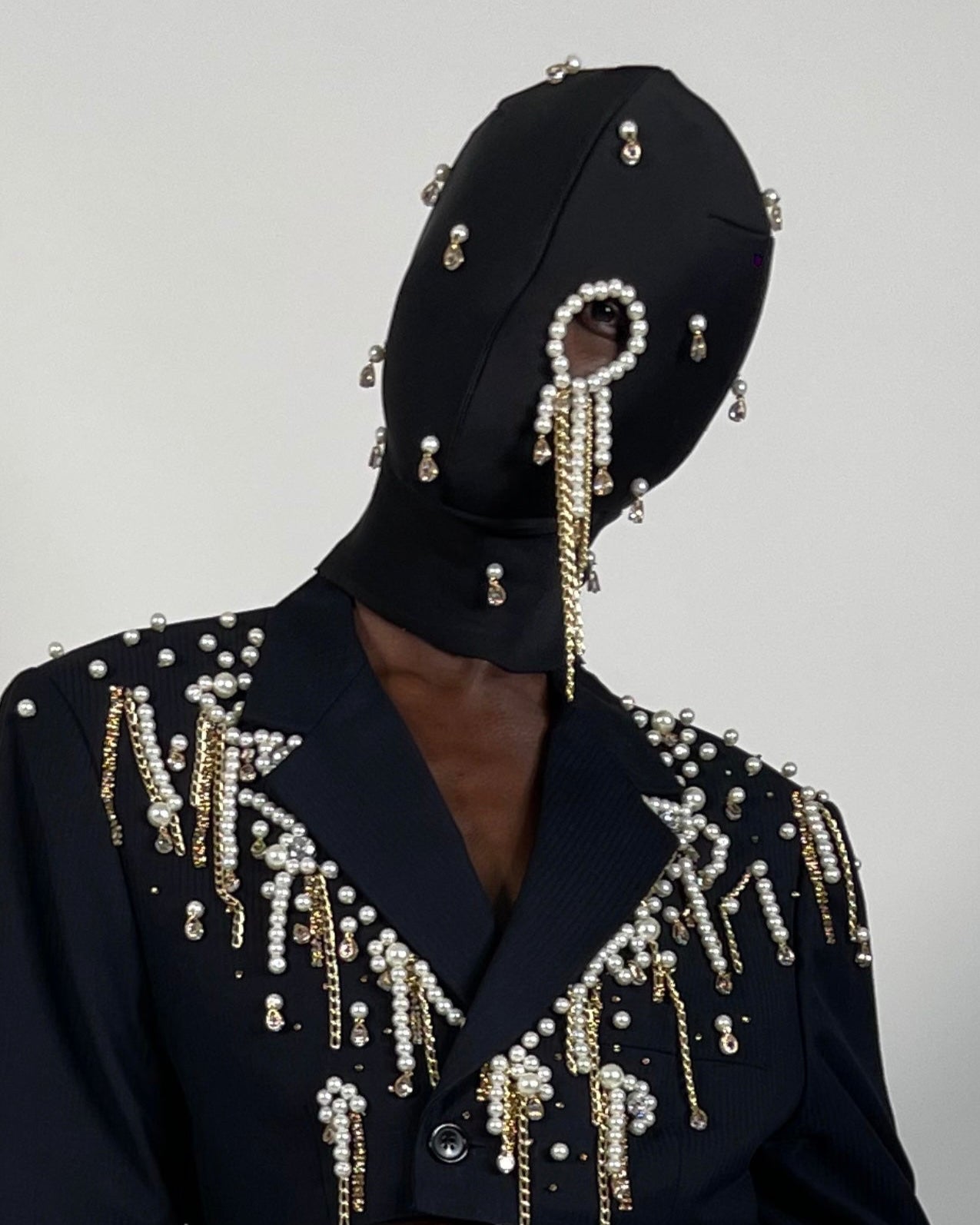 Nadéne luxury black fashion mask with pearls and gold plated chains, one eye cut-out design.